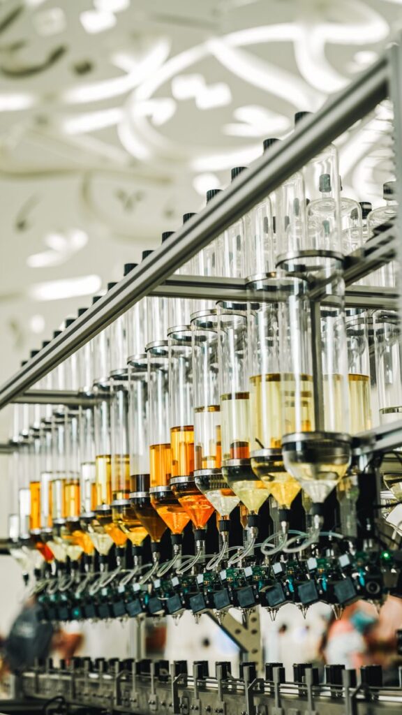 Close-up of automated bottle filling machinery in Dubai factory with colorful liquids.